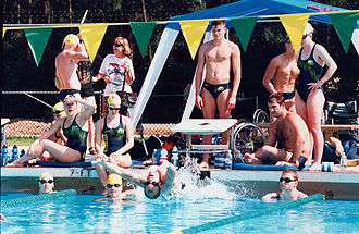 Swimmers posed in a group shot around the edge of a pool