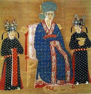 A square painting of a woman in an intricately decorated blue dress and a large blue hat, sitting in a throne. She is flanked by two female attendants in black dresses with flower covered black hats.