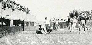 Touchdown photographed from the side, with fans in an end-zone grandstand