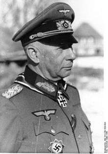 A man wearing a military uniform and peaked cap with an Iron Cross displayed at the front of his uniform collar.