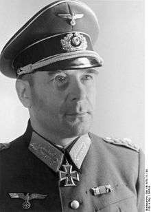 A man wearing a military uniform and peaked cap with an Iron Cross displayed at the front of his uniform collar.