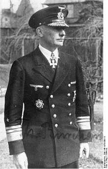 A man wearing a military uniform and peaked cap with a military order in shape of a cross displayed at the front of his uniform collar.