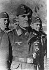 A man wearing a military uniform, side cap, various military decorations including an Iron Cross displayed at the front of his uniform collar.