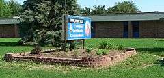 One-story 1970s building; sign in front with picture of pope, horseman, inscription "Pope John XXIII Central Catholic Crusaders"