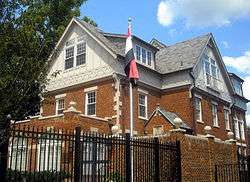 A large brick house with the flag of Iraq on a flagpole.