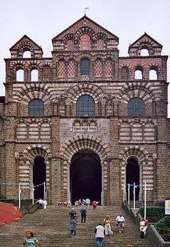 A highly ornamental church facade built in alternating courses of red and white stone.