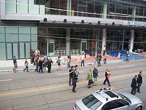 people milling around King Street in front of the TIFF Bell Lightbox, with rails and ropes set up around a carpets in front of the building