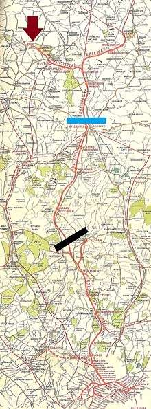 Map of a long railway line, ending at one end in a fork to two termini, and at the other end in a loop with a number of closely packed stations.