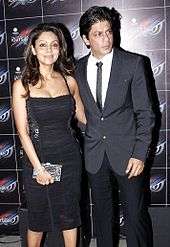 Shah Rukh Khan standing beside his wife Gauri at a party in 2012