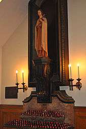 An image of a religious statue of a woman surrounded by candles