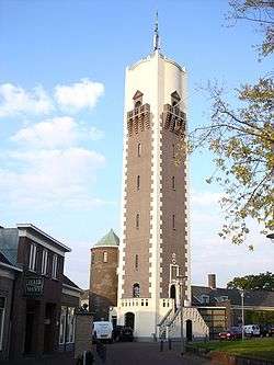 A water tower standing in the middle of several small, end 19th-century houses