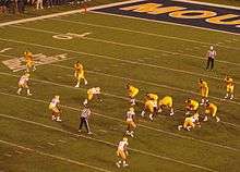 American football players line up for a play in a full stadium.