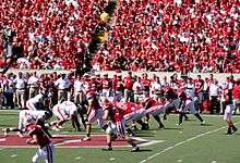 American football line up for a play in a full stadium.